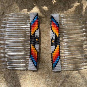 May include: Two beaded hair combs with a colorful geometric design. The combs are white with orange, yellow, red, blue, and black beads.