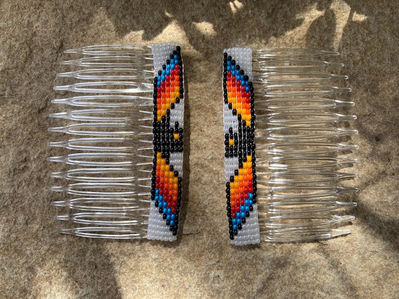 May include: Two beaded hair combs with a colorful geometric design. The combs are white with orange, yellow, red, blue, and black beads.
