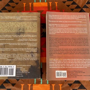 Pode incluir: Dois livros de bolso com capas coloridas s&atilde;o exibidos em um tecido estampado. Os livros apresentam texto e um c&oacute;digo de barras. Um livro &eacute; intitulado "The 7th Precinct on an Indian reservation, a murder mystery laced with mysticism, politics, and social commentary."