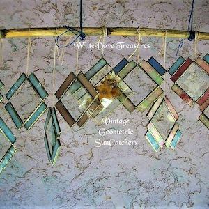 May include: A collection of vintage geometric stained glass suncatchers hanging from a bamboo rod. The suncatchers are made of various colors of glass, including blue, green, pink, and brown. The text "White Dove Treasures" and "Vintage Geometric Suncatchers" is visible in the image.