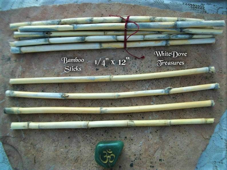 Op de afbeelding: Een bundel natuurlijke bamboestokken van 6,35 mm dik en 30,48 cm lang. De stokken zijn lichtbruin met een witte coating. De tekst "Bamboo Sticks" en "White Dove Treasures" is zichtbaar in de afbeelding.