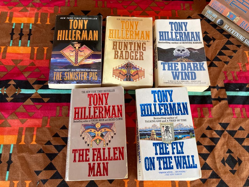 Pode incluir: Cinco livros de capa dura de Tony Hillerman s&atilde;o exibidos. Os t&iacute;tulos incluem "The Sinister Pig", "Hunting Badger", "The Dark Wind", "The Fallen Man" e "The Fly on the Wall". Os livros t&ecirc;m capas coloridas com ilustra&ccedil;&otilde;es.