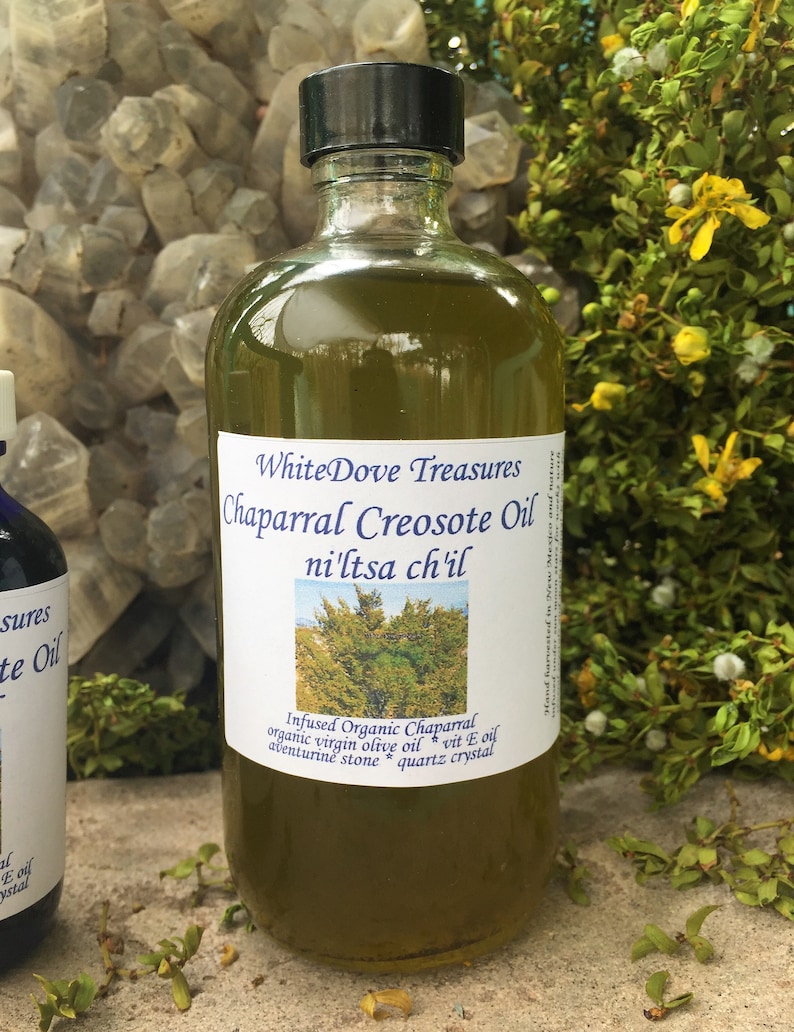 May include: A glass bottle of Chaparral Creosote Oil infused with organic virgin olive oil, aventurine stone, and quartz crystal. The label reads "WhiteDove Treasures Chaparral Creosote Oil ni'ltsa ch'il".