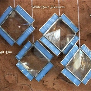 May include: Five light blue diamond-shaped stained glass ornaments with clear glass centers. The ornaments are hanging from white strings. The text "White Dove Treasures" is visible in the top right corner of the image. The text "Light Blue" is visible in the bottom left corner of the image.