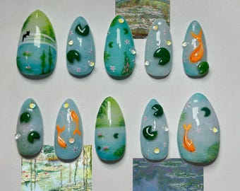 May include: A set of ten almond-shaped artificial nails with a water lily pond design. Each nail features a different design, including koi fish, lily pads, and a cat silhouette. The nails are painted in shades of blue, green, and orange.