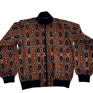 May include: A zip-up bomber jacket featuring a repeating pattern of black and white oval shapes on a rust-colored background. The jacket has black cuffs, a black collar, and a black zipper.