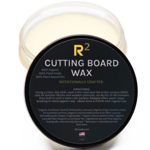 May include: A jar of cutting board wax with a black label. The label reads "CUTTING BOARD WAX" and includes directions for use. The wax is 113 grams and made with organic, food-grade, and plant-based oils.