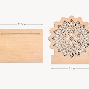Op de afbeelding: Een lichtgekleurde rechthoekige houten basis met een gleuf van 29,21 cm bij 21,59 cm, en een apart rond houten stuk met een lasergesneden mandalapatroon van 29,21 cm hoog en 27,94 cm breed.