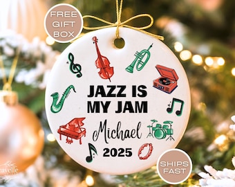May include: White ceramic ornament with musical instrument illustrations and the text "JAZZ IS MY JAM Michael 2025". Includes a violin, trumpet, saxophone, piano, drums, and musical notes. A gold string is attached for hanging.