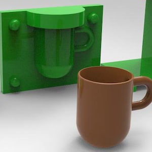 Może przedstawiać: Brązowy kubek z zakrzywionym uchwytem stoi obok zielonych geometrycznych kształtów, w tym formy do kubka. Kubek i forma znajdują się na białej powierzchni. Kubek ma około 10 cm wysokości.