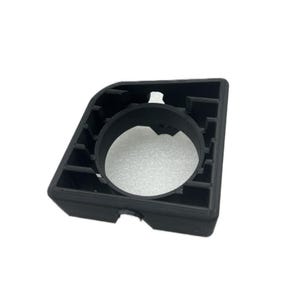 May include: A black, angular plastic component with a large circular opening and a grid-like structure. The object has a rectangular shape with a beveled edge and appears to be 3D-printed.