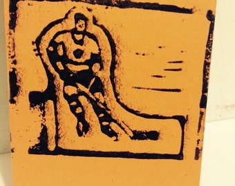 Handmade linocut orange note card with toy rod hockey guy