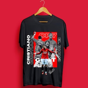 Puede incluir: Camiseta negra con un collage de Cristiano Ronaldo en acción, con el texto "CR7" y "EL Bicho". La camiseta también incluye las palabras "Cristiano" y "GOAT".