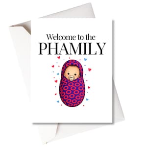 May include: A white greeting card with the text "Welcome to the PHAMILY" in black. The card features an illustration of a baby wrapped in a red and blue patterned blanket, with red and blue hearts scattered around the baby.