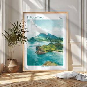 May include: A framed art print of Labuan Bajo, Indonesia, featuring a watercolor landscape of green hills, turquoise waters, and a blue sky. The print includes the text "Labuan Bajo", "Flores", and "Indonesia" in teal.