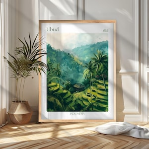 May include: A framed art print featuring a vibrant landscape of Ubud, Bali, Indonesia. The artwork depicts lush green rice terraces, palm trees, and a small village nestled in the valley. The print is in a light wood frame.