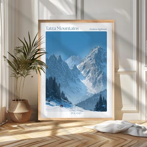 May include: A framed print of the Tatra Mountains in Poland. The image features snow-covered peaks under a bright blue sky. The text "Tatra Mountains" and "Southern Highlands" are at the top, with "POLAND" at the bottom. The print is in a light wood frame.