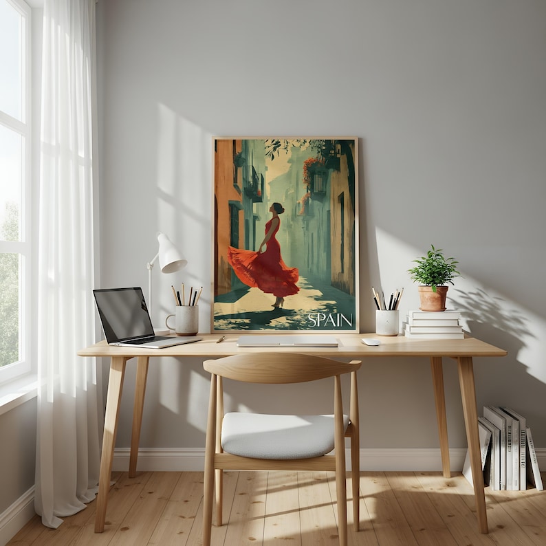 K&ouml;nnte beinhalten: Ein gerahmter vertikaler Wandkunstdruck mit einer stilisierten Illustration einer Person in einem flie&szlig;enden roten Kleid in einer engen Gasse, mit dem Wort SPAIN am unteren Rand. Das Kunstwerk steht auf einem Holztisch mit einem Laptop.