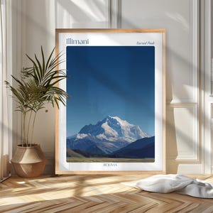 Può includere: Una stampa incorniciata con un paesaggio montano sotto un cielo azzurro. L'opera d'arte include il testo "Illimani" e "Sacred Peak" in alto e "Bolivia" in basso. La montagna ha una vetta innevata.