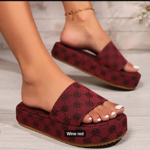 Peut inclure: Sandales compensées rouge vin avec un motif répétitif. Les sandales ont une semelle épaisse et une seule bride sur le dessus du pied. Le texte "Wine red" est visible en bas de l'image.