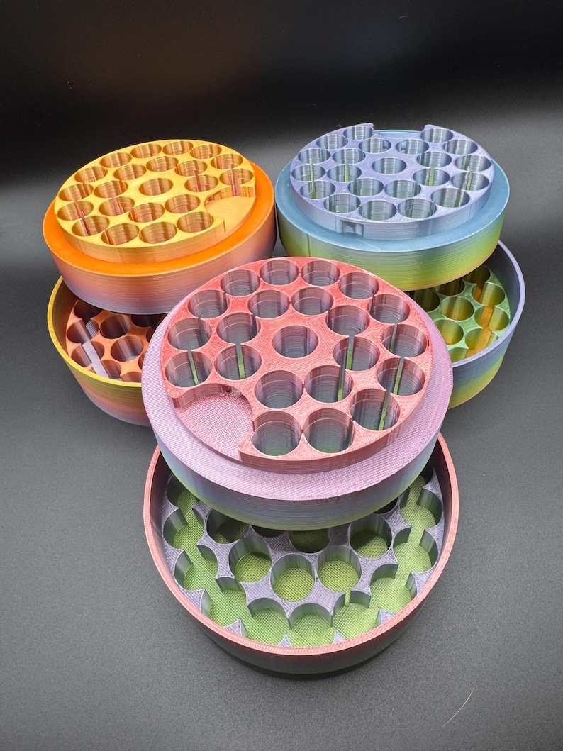 May include: A collection of colorful, 3D-printed storage containers. Each container is round with multiple circular holes on the top and a matching base. The colors include orange, pink, purple, blue, and green, with some containers displaying a rainbow gradient.
