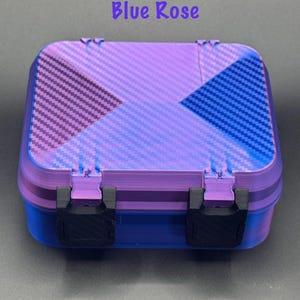 May include: A rectangular storage box with a purple and blue carbon fiber pattern on the lid. The base is solid blue, and the lid features two black plastic latches. The text Blue Rose is printed in purple above the box on a dark background.