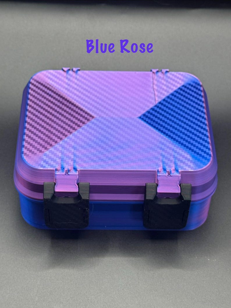 May include: A rectangular storage box with a purple and blue carbon fiber pattern on the lid. The base is solid blue, and the lid features two black plastic latches. The text Blue Rose is printed in purple above the box on a dark background.