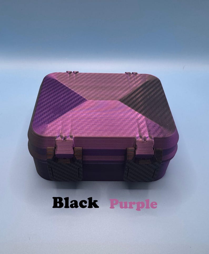 May include: A square storage box with a hinged lid featuring a purple and black carbon fiber pattern. The box has two dark-colored latches on the front. Below the box, the text Black Purple is printed in black and purple font respectively.