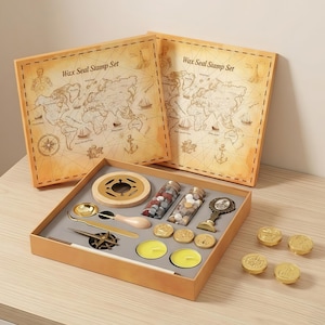 Może przedstawiać: Zestaw stempli do pieczętowania woskiem w stylu vintage w drewnianym pudełku. Zestaw zawiera pudełko z motywem mapy, narzędzie do topienia wosku, łyżkę, koraliki woskowe, świece i kilka złotych pieczęci woskowych. Pudełko jest oznaczone "Wax Seal Stamp Set."