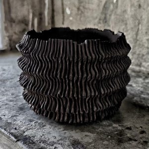Vaso in argilla nera fatto a mano, con texture ondulata, perfetto per l'arredamento moderno e rustico.