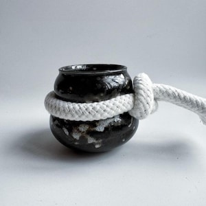 May include: A set of three ceramic mugs with a speckled, matte finish. The mugs are in shades of cream, light gray, and dark gray. Each mug has a simple, minimalist design, perfect for coffee or tea.