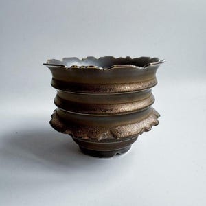 May include: A set of three ceramic mugs with a speckled, matte finish. The mugs are in shades of cream, light grey, and dark grey. Each mug has a simple, minimalist design, ideal for coffee or tea.