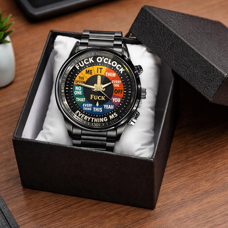 May include: Black wristwatch with a unique dial design. The watch face features a colorful graphic with the text "FUCK O'CLOCK" and various phrases. The watch is presented in a black gift box, making it a distinctive accessory.