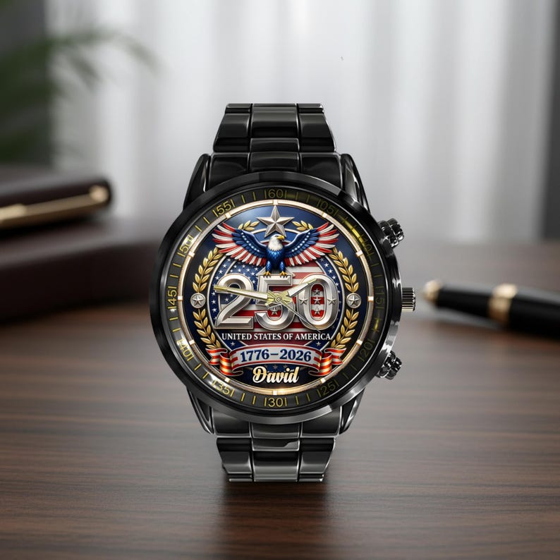 May include: Black wristwatch with a round face featuring a patriotic design. The watch face displays the number 250, an eagle, and the text "United States of America 1776-2026". The watch has a black metal band and a personalized name.