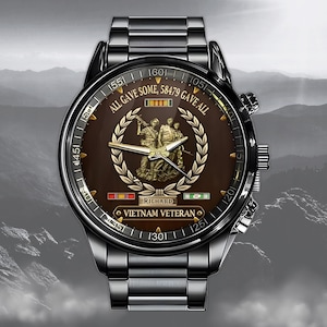 May include: A stainless steel watch with a brown face featuring a gold emblem of soldiers and the text "ALL GAVE SOME, 58479 GAVE ALL". The watch has a black bezel and a metal band. The words "VIETNAM VETERAN" are also visible.