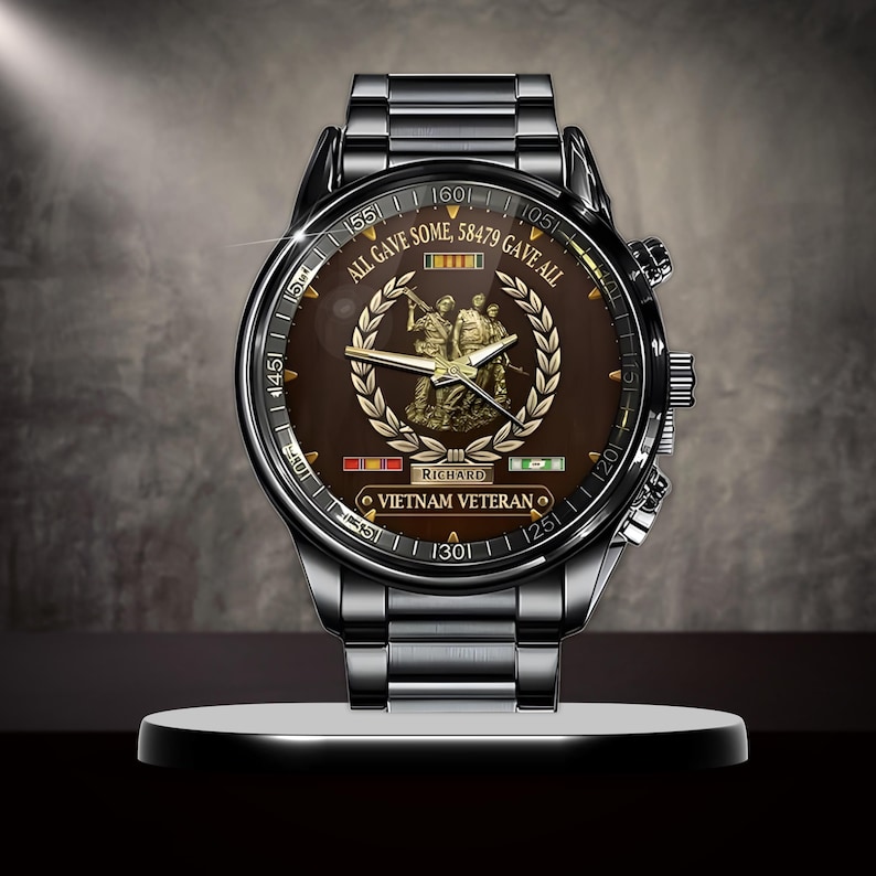 May include: A stainless steel watch with a brown face featuring the text "ALL GAVE SOME, 58479 GAVE ALL" and "VIETNAM VETERAN". The watch has a detailed illustration of soldiers and a laurel wreath.
