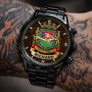 May include: Black wristwatch with a brown face featuring a coat of arms design, a Puerto Rican flag, and the name "RICHARD". The watch has a black metal band and a detailed dial with numbers and markings.