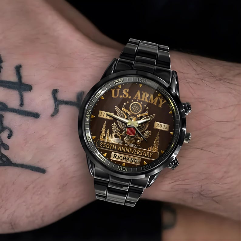 May include: Black wristwatch with a brown face featuring the text "U.S. ARMY" and an eagle emblem. The watch also displays "250TH ANNIVERSARY" and the name "RICHARD". The watch is on a black metal band.
