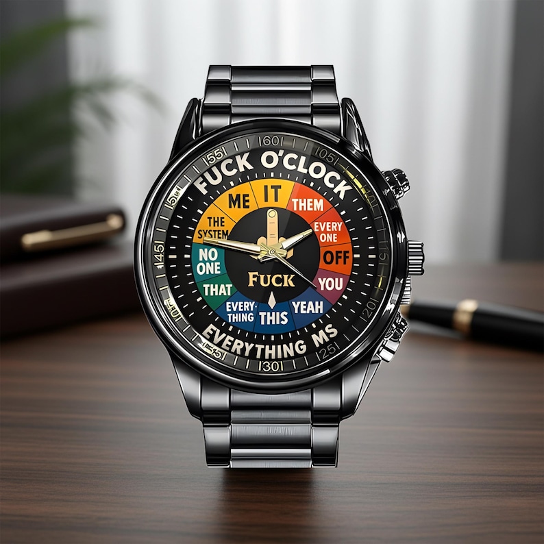 May include: Black wristwatch with a round face featuring the text "FUCK O'CLOCK" in a circular design. The watch face has a black background with colorful segments and gold hands. The watch band is black metal.