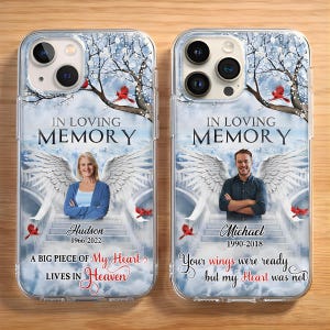 May include: Two clear phone cases with a memorial design. Each case features a person with angel wings, the text "IN LOVING MEMORY", and dates. One case says "A BIG PIECE OF My Heart LIVES IN Heaven". The other says "Your wings were ready but my Heart was not".