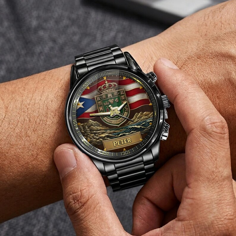 May include: A black metal wristwatch with a round face featuring the Puerto Rican flag, a central heraldic crest with a lamb, and the name PETER printed on a gold-toned rectangular plaque. The watch has a black link band and three side buttons.