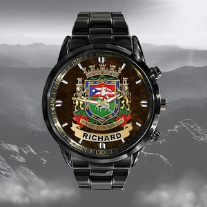 May include: Black wristwatch with a brown face featuring a coat of arms design and the name "RICHARD" in white. The watch has a black metal band and a detailed dial with numbers and markings.
