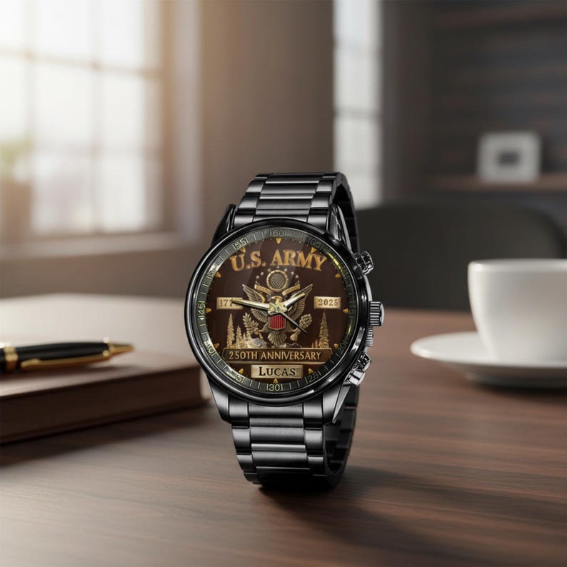 May include: A black wristwatch with a metallic band and a brown face. The watch face features the text "U.S. ARMY 250TH ANNIVERSARY" and the years "1775" and "2025". The watch is displayed on a wooden surface.
