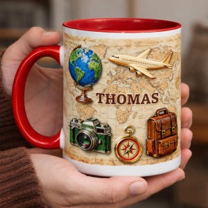 May include: White ceramic mug with a red interior and handle, featuring a world map design. The mug is decorated with travel-themed illustrations, including a globe, airplane, camera, compass, and suitcase. The name "THOMAS" is printed on the mug.
