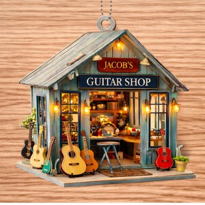 May include: Miniature guitar shop ornament with the text "Jacob's Guitar Shop." The shop is painted blue with a green roof and features several guitars displayed outside. The interior is visible through the open door.