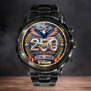 May include: Black wristwatch with a patriotic design. The watch face features a blue background with a bald eagle, stars, and the text "250 United States of America 1776-2026". The watch band is black.