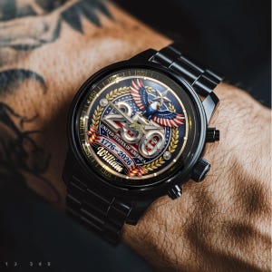 May include: Black wristwatch with a detailed face featuring a patriotic design. The watch face displays the number 250, an eagle, and the text "UNITED STATES OF AMERICA 1776-2026 William". The watch has a black metal band.