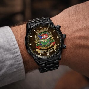 May include: Black wristwatch with a personalized face. The watch features a detailed crest design with the name "RICHARD" on a banner. The watch has a black metal band and a dark brown watch face with gold accents.