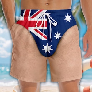 May include: Swim shorts featuring the Australian flag design with a blue background, white stars, and a red, white, and blue Union Jack pattern. The shorts include a white drawstring at the elasticised waistband and a standard leg length.