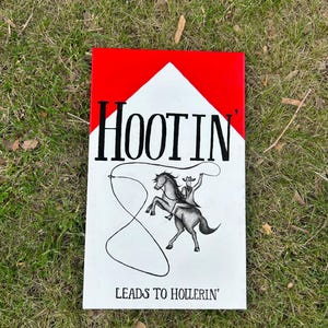 Può includere: Un cartello rettangolare con un design rosso e bianco che presenta il testo nero HOOTIN' in alto e LEADS TO HOLLERIN' in basso. Al centro, un'illustrazione in bianco e nero raffigura un cowboy su un cavallo rampante che tiene un lazo.